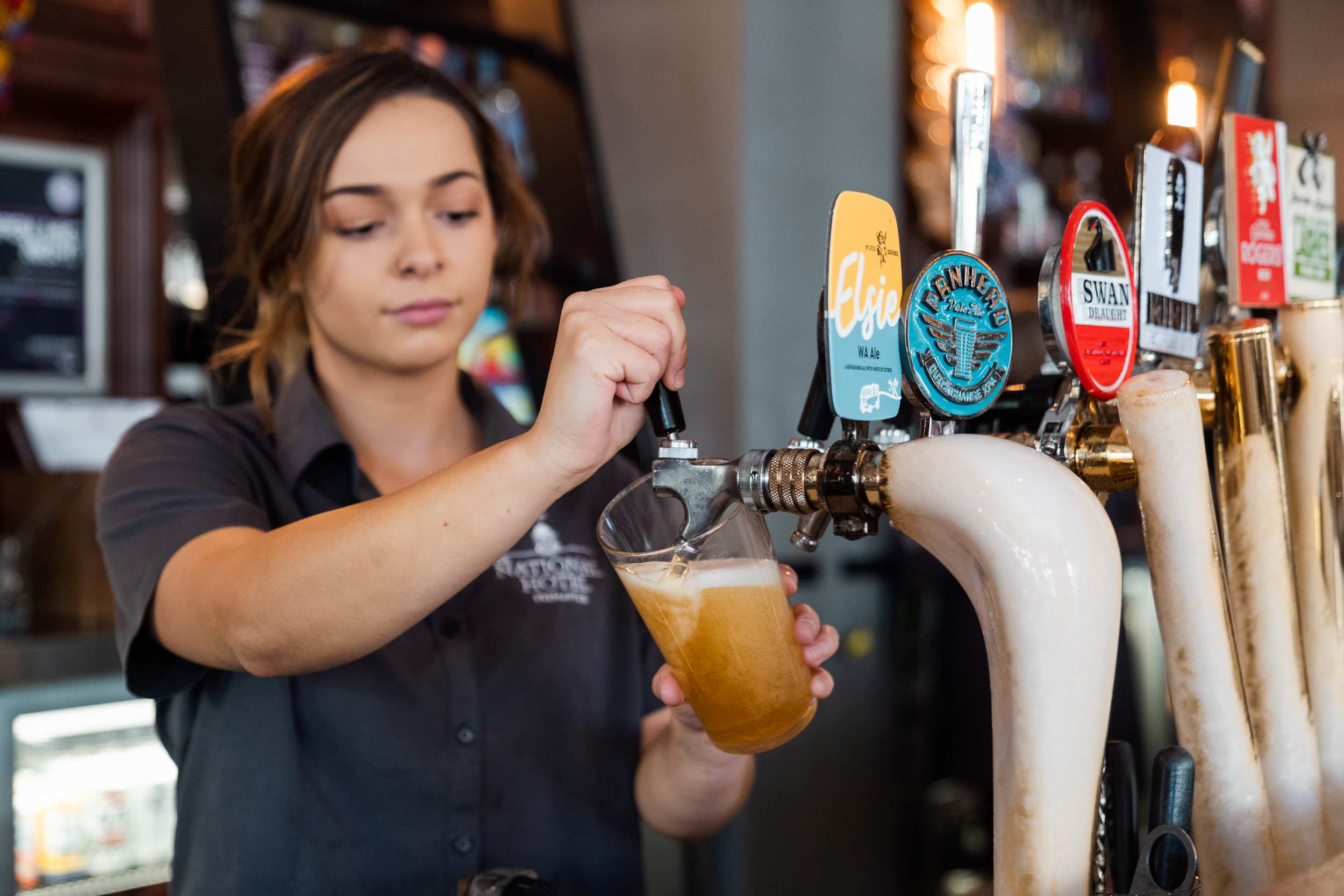 Young female bartender pulls a pint