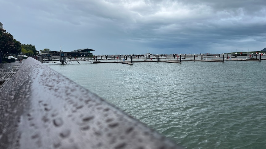 An empty harbour with raindrops on a handrail .