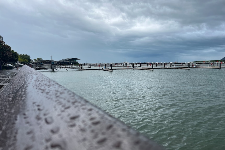 An empty harbour with raindrops on a handrail 
