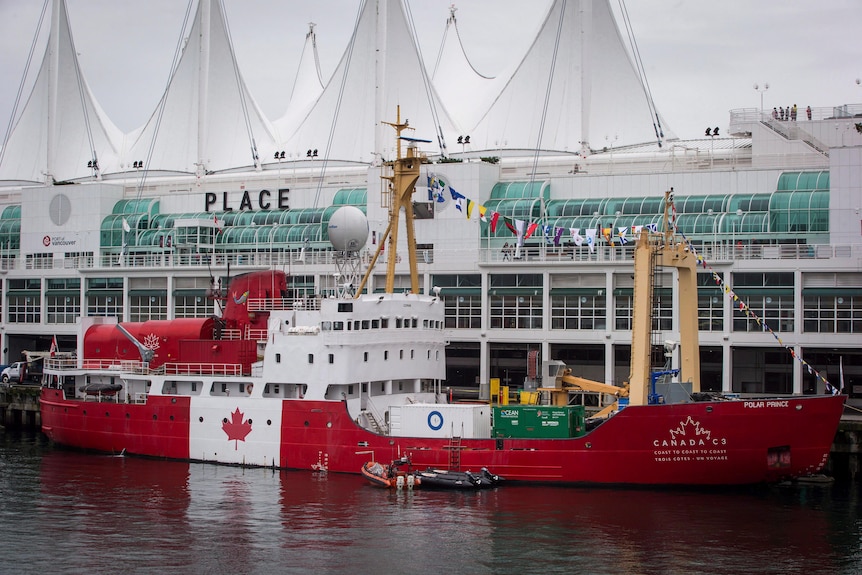 A boat painted in the bright red and white of the Canadian flag (including a maple leaf) floats in the Port of Vancouver.