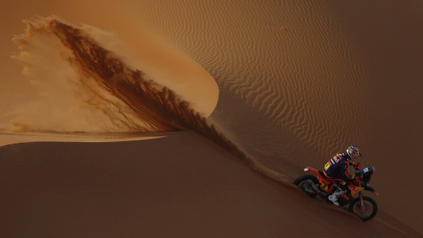 Toby Price rides down the face of a dune