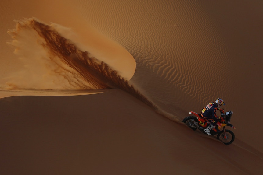 Toby Price rides down the face of a dune