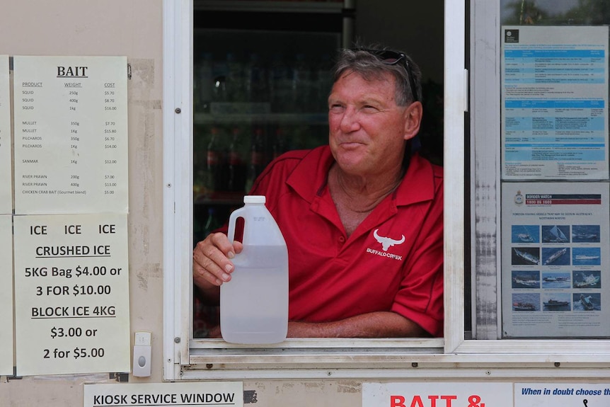 Ray Medlicott stands at the window to his kiosk with a bottle of vinegar.