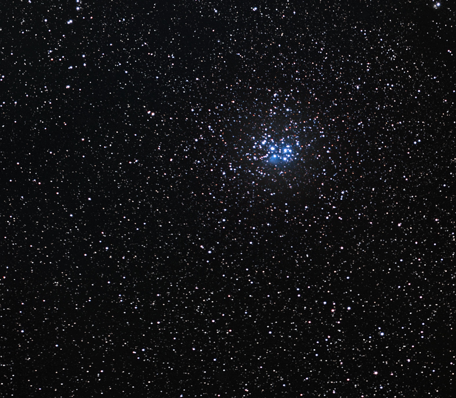 A small cluster of stars that look blue appear in a dark night sky