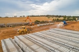 Large stacks of sleepers are being taken of rail carriages and stacked by cranes.