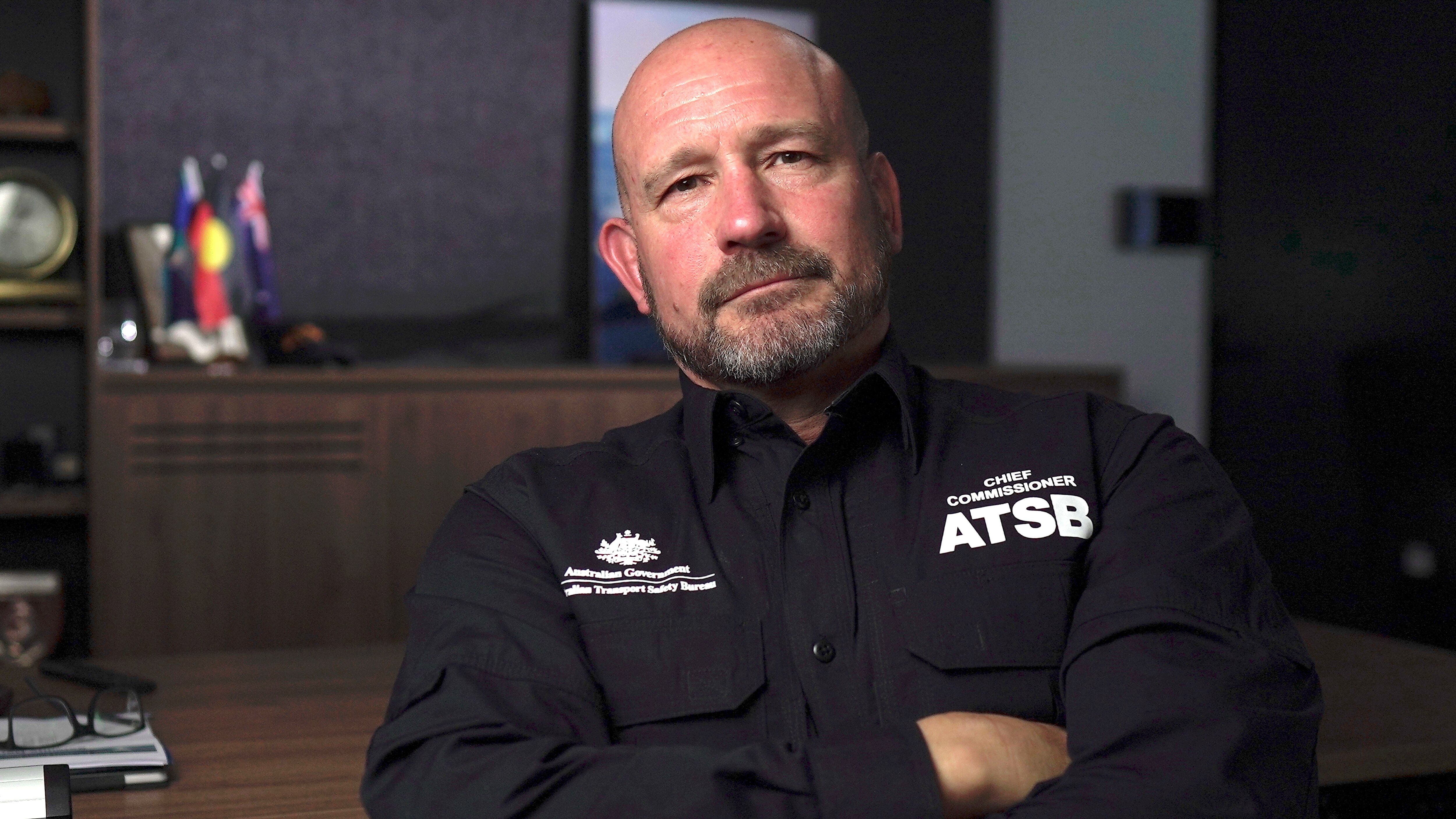 Man wearing an ATSB uniform sitting in an office with his arms folded.