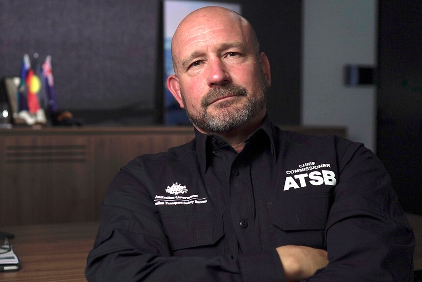 Man wearing an ATSB uniform sitting in an office with his arms folded.