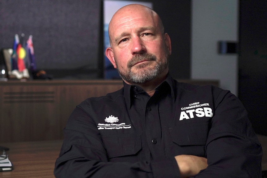Man wearing an ATSB uniform sitting in an office with his arms folded.