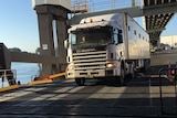 Truck driving down ramp on to ferry.