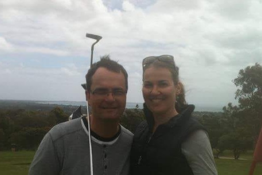 A man and a woman posing on the golf course.