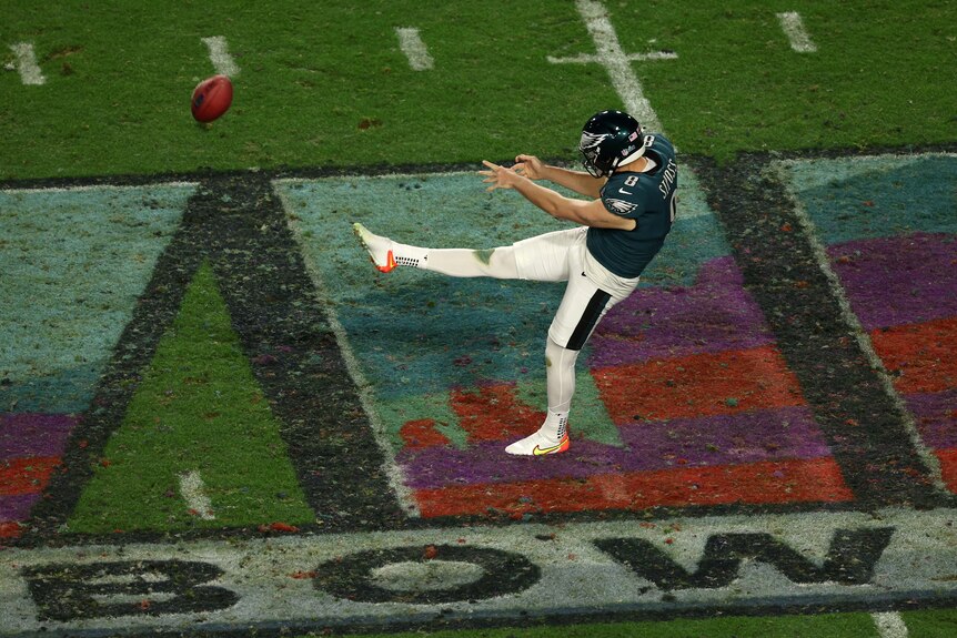 Australian NFL punter Arryn Siposs extends his right leg as he kicks the ball downfield during Super Bowl LVII.