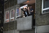 People applaud and hold up a sign saying thank you NHS from a balcony.