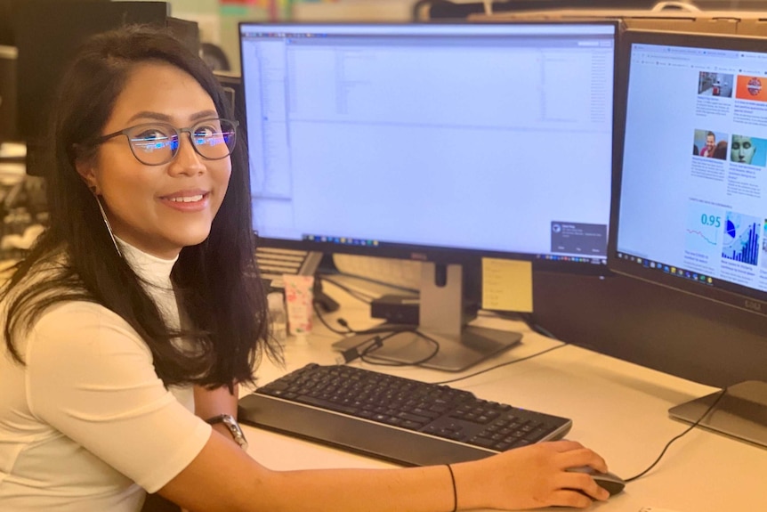 Girl in glasses sitting in front of a computer.