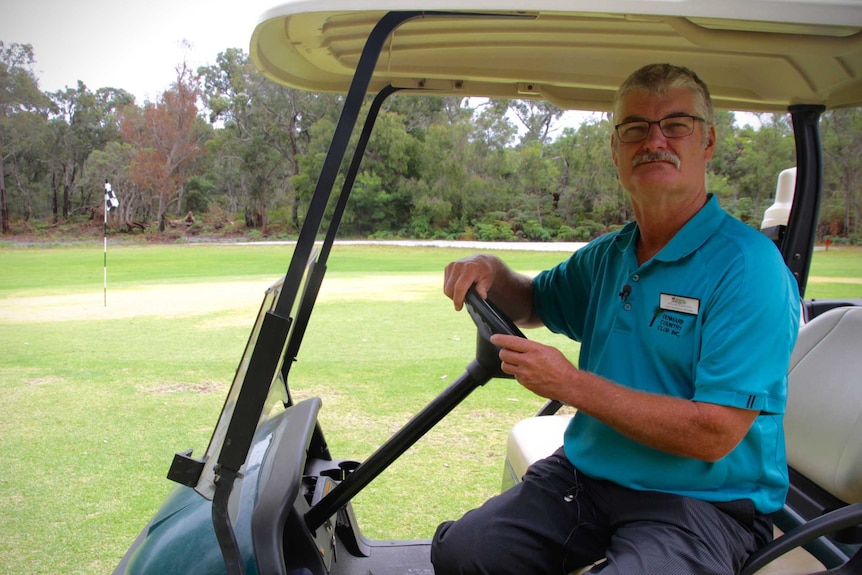 A man sits in a golf buggy on a golf green damaged by chemicals