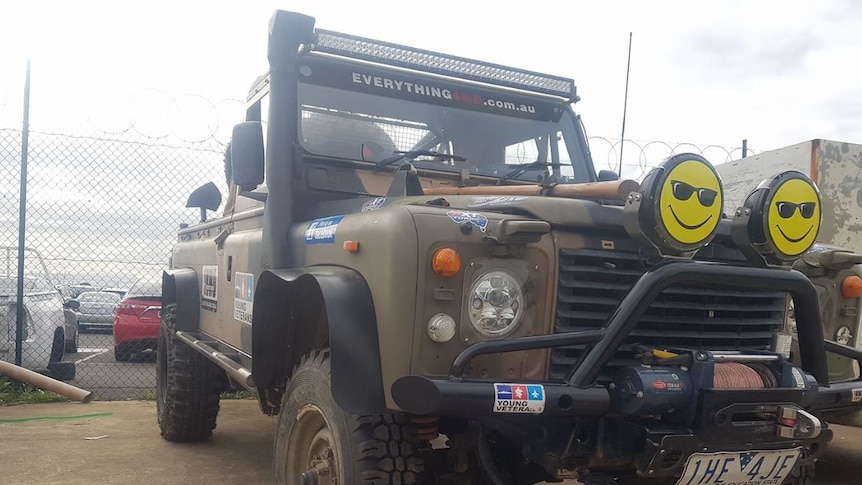 A close shot of a modified decommissioned Army Land Rover with smiley faces above the bull bar.