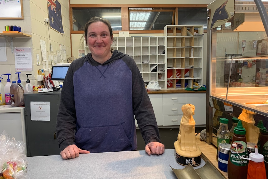 A young woman stands at a shop counter and smiles