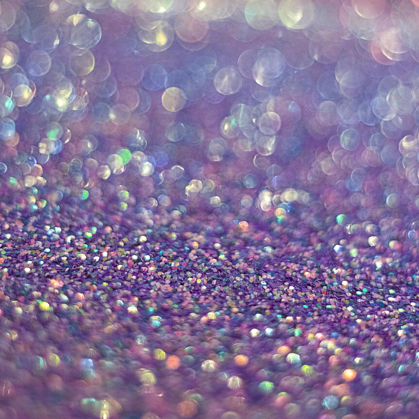 Close up generic shot of light purple glitter sparkling with pink, blue and green. 