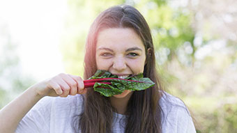 Young woman eating raw leafy green vegetables.