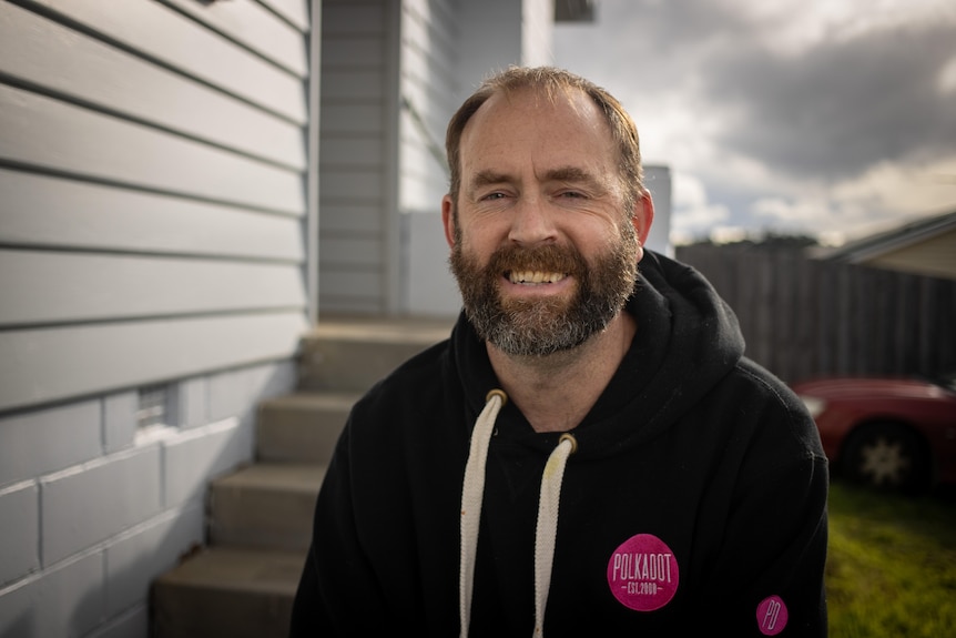   A bearded man in a hoodie smiles