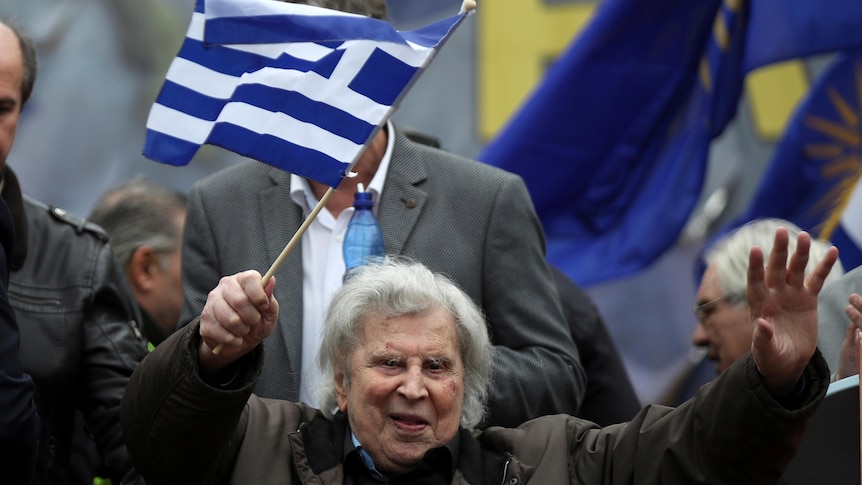 Mikis Theodorakis waves a Greek flag