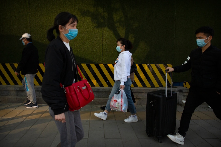 Masked commuters walk down the street in Beijing