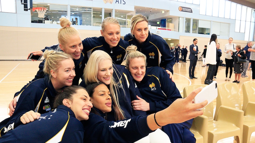 Lauren Jackson poses for a photo with the Australian team after announcing her retirement from basketball.