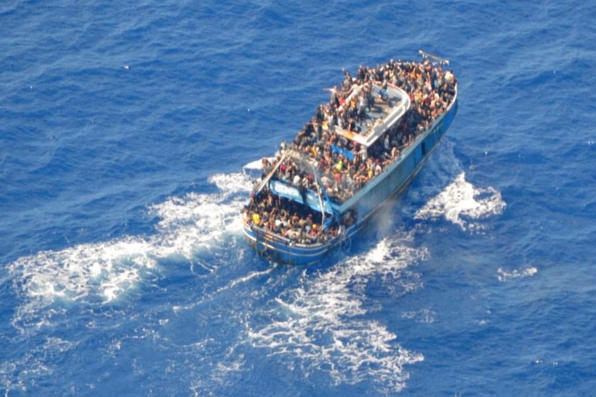 An aerial photo shows an overcrowded boat on a blue sea.