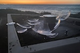 photo of broken pieces of an acrylic sphere laying on a concrete platform with the evening sky and ocean in the background
