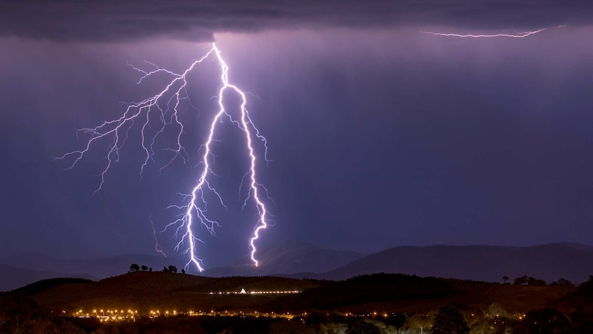 Lightning splits and hits in the hills overlooking Canberra at night.