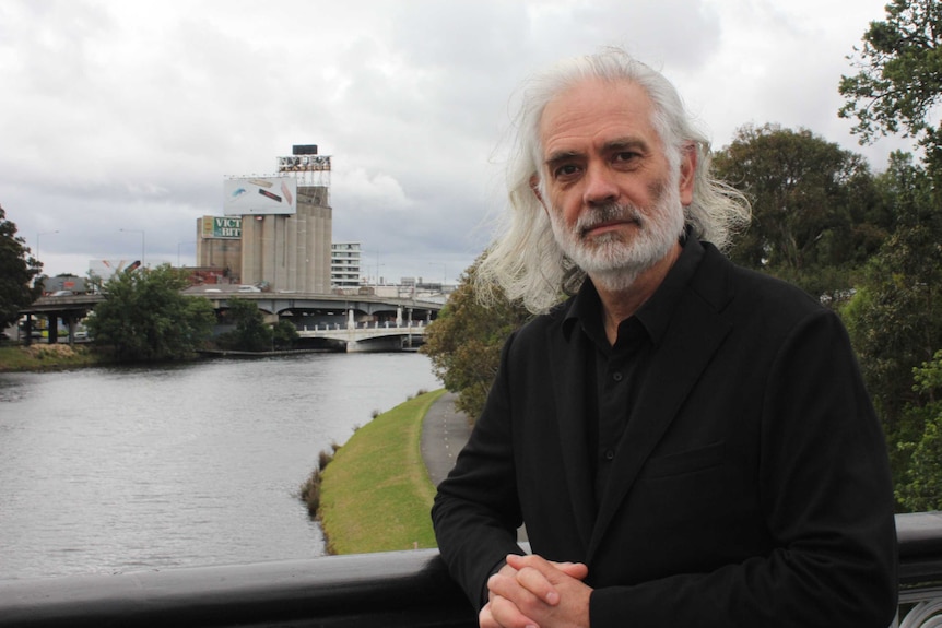 David Sutherland, lead architect on the Nylex clock restoration,  stands by the Yarra River with the clock in the background.