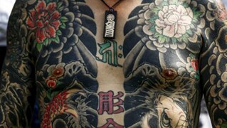 A man shows his traditional full body tattoo, with flower motifs, as he poses outside the Sensoji temple in Tokyo.