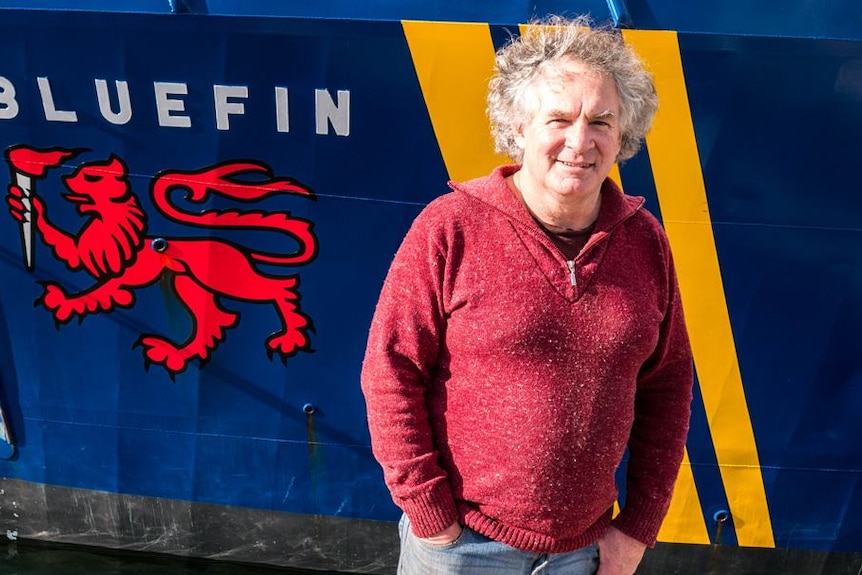 University of Tasmania researcher Neville Barrett poses in front of a ship.