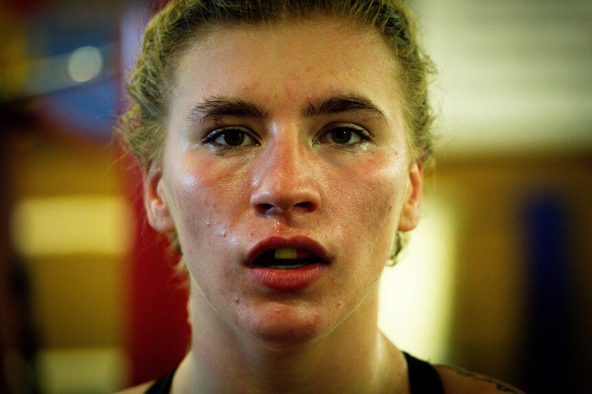 Headshot of boxer Marissa Williamson-Pohlman, exhausted, sweating, wearing mouthguard