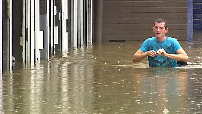A man wades through floodwaters in Gympie.