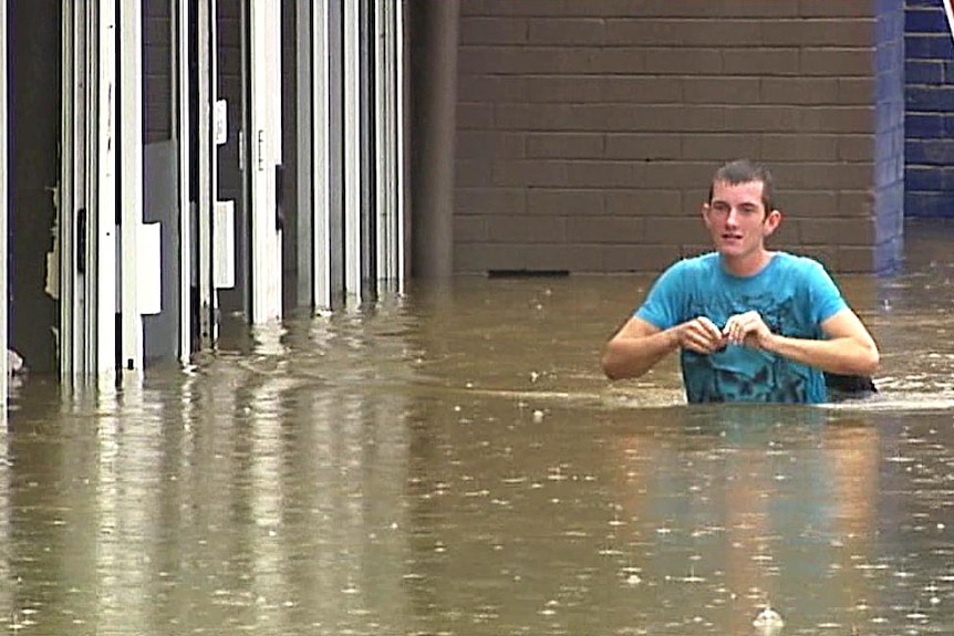 A man wades through floodwaters in Gympie.