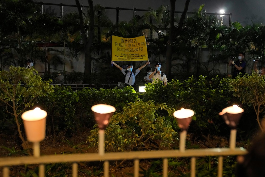 A police officer holds up a placard to warn people lighting candles to mark the anniversary of the military crackdown