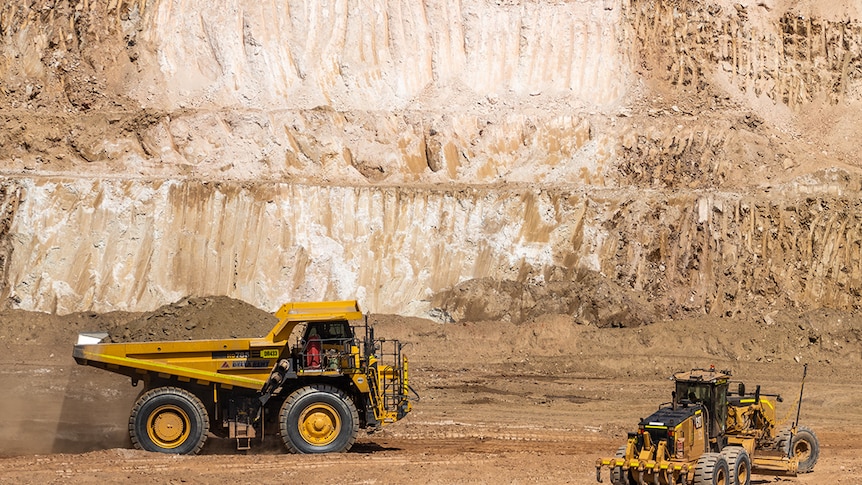 a mine site with a big truck and white rock