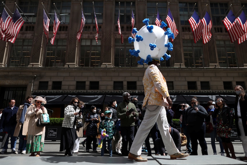 A person dressed in a costume symbolising COVID-19 walks on a makeshift runway 