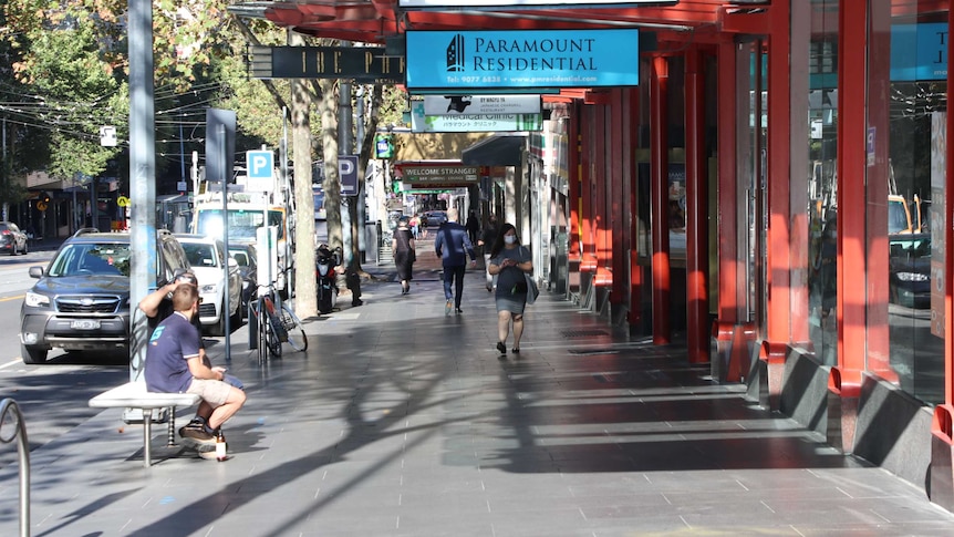 A few people on a footpath in the normally busy Bourke St.