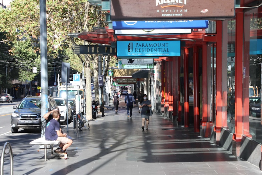 A few people on a footpath in the normally busy Bourke St.