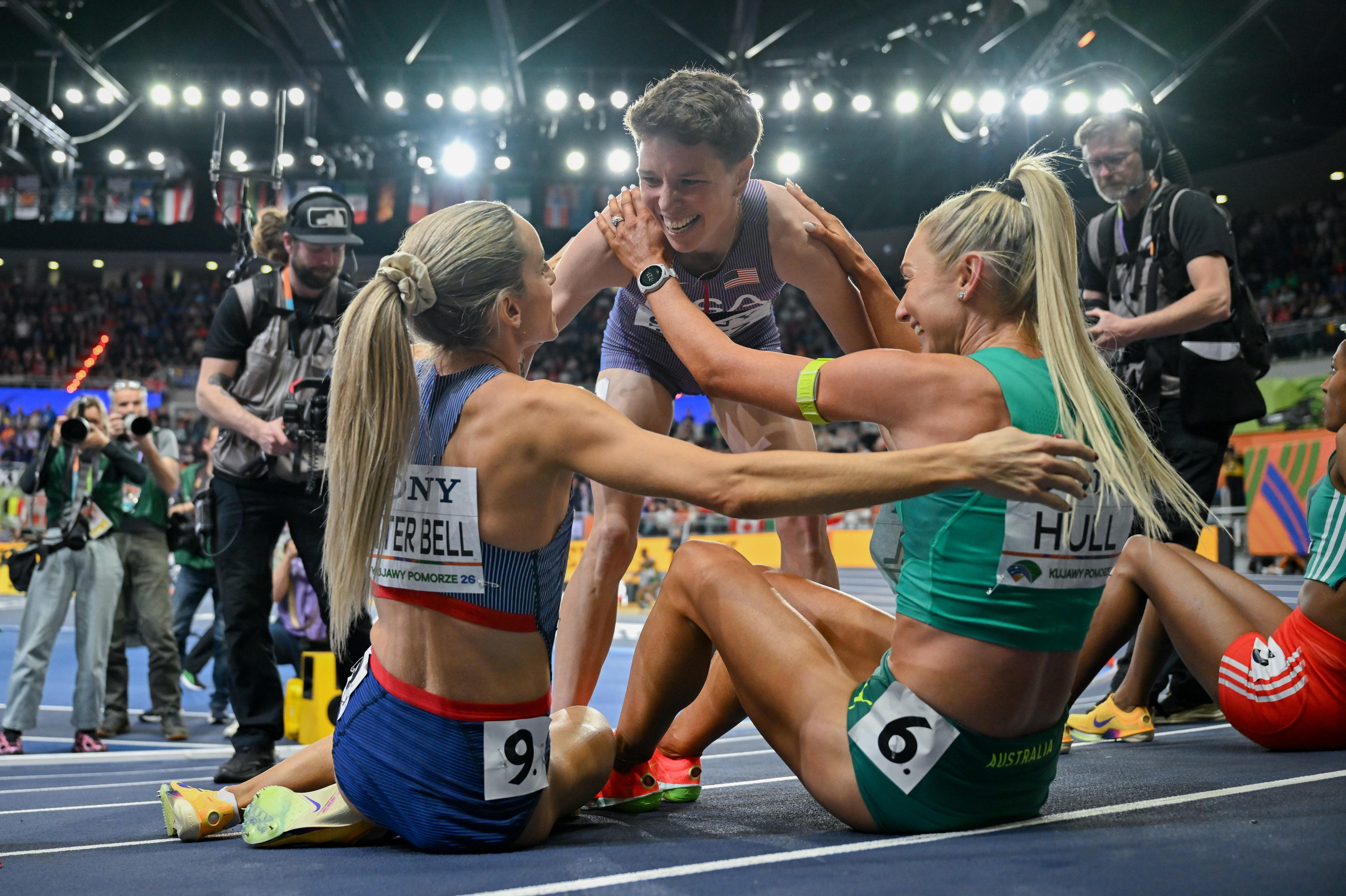 Nikki Hiltz (standing) hugs Georgia Hunter Bell and Jess Hull (sitting) after the 1,500m at the world indoor championships.