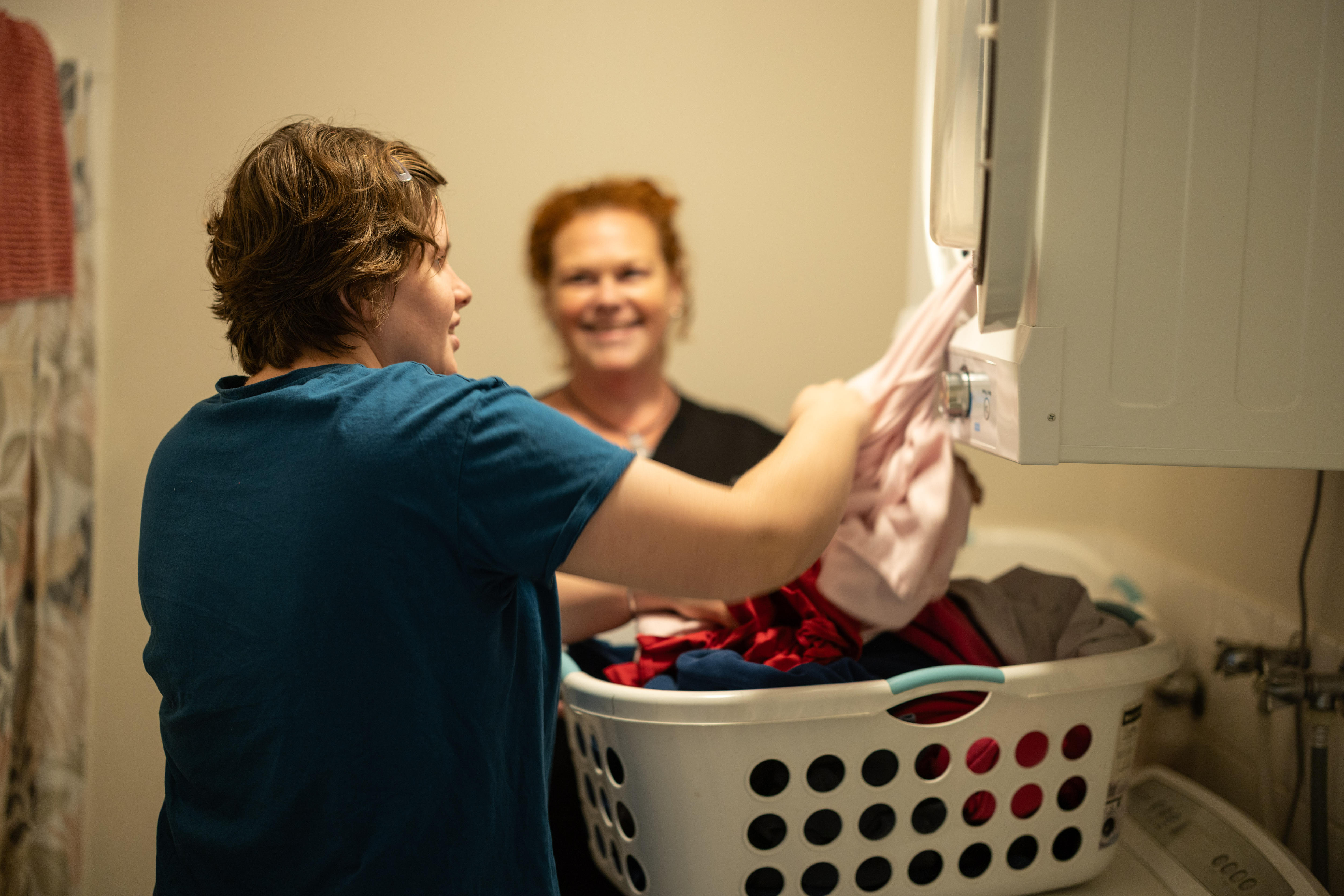 A young adult woman being supervised while using a clothes dryer