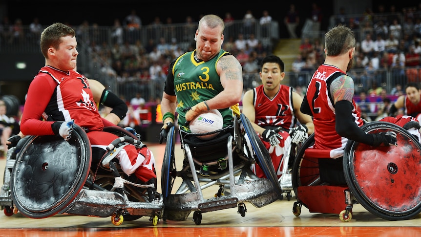 Australia's Ryley Batt (C) moves past Canada's Zak Madell (L) in wheelchair rugby final in London.