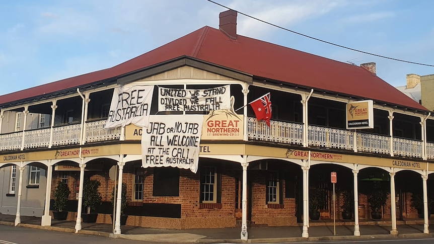 The exterior of a hotel with signs reading 'free australia, and anti vaccination messages