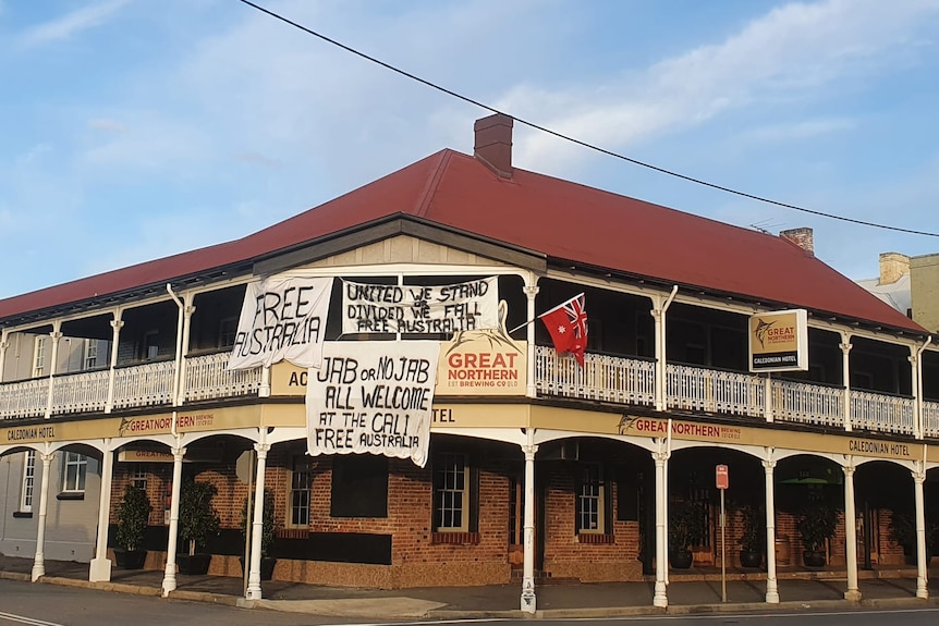 The exterior of a hotel with signs reading "free Australia" and others putting forth anti-vaccination messages.