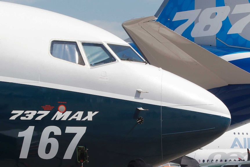 A Boeing 737 MAX nose is shown close-up, with the tail of a Boeing 787 and the fuselage of an Airbus A380 behind it.