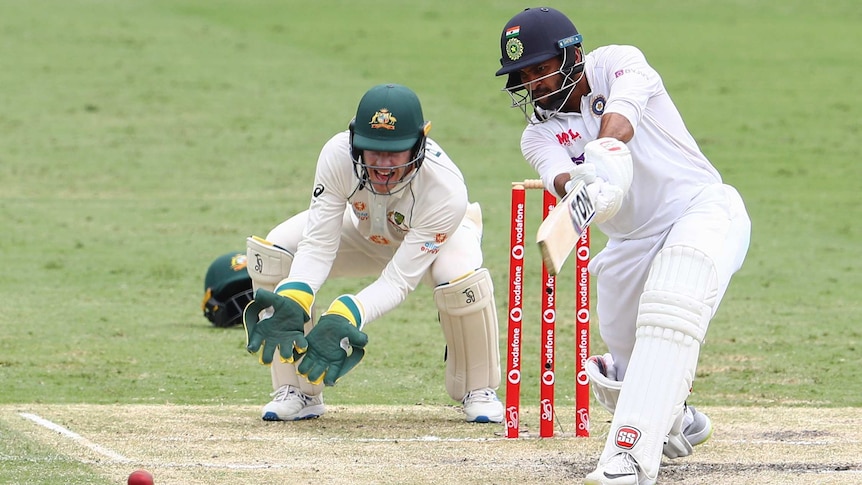 Indian batsman Shardul Thakur drives as Australian wicketkeeper Tim Paine looks on at the Gabba.