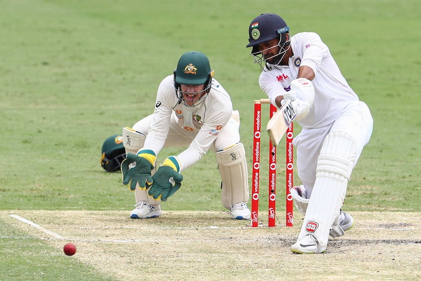 Indian batsman Shardul Thakur drives as Australian wicketkeeper Tim Paine looks on at the Gabba.