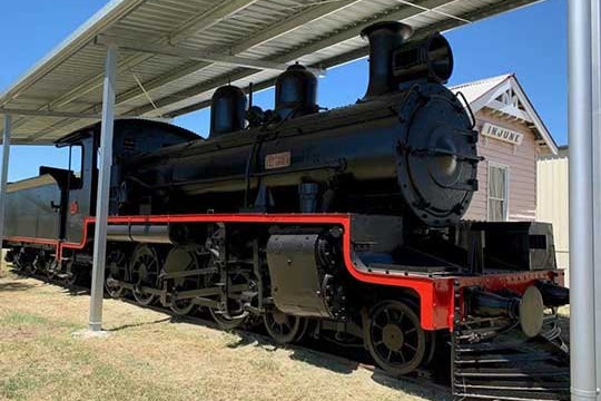 Restored red and black steam train on display at Injune.
