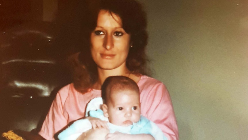 A mother sits with her baby son on her lap